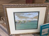 Large custom framed signed painting showing harbor scene with boats and buildings under a cloudy sky, ornate gold frame