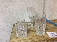 Photo showing four different styles of cut glass drinkware including tumblers, highball glasses, and wine glasses.