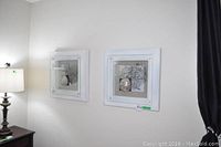 Two white framed shadow boxes mounted on a wall above a lamp, showing of the two beach inspired decor pieces.