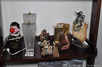 Photo of wooden shelf showing all decorative items included in the lot: lamp, candle holders, clock, figurines, and sculpture.