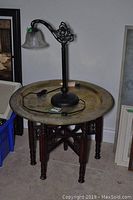 Brass decorative plate on carved wooden base with table lamp on top, showing overall lot contents and features.