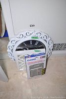 Casio printing calculator in packaging in front of two framed decorative mirrors and a framed clock with ornate white frame