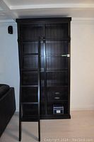 Front view of the bookcase showing six shelves and attached sliding ladder.