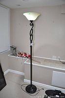 Full view of the black metal floor lamp with twisted design and frosted glass shade standing approximately 72 inches tall.