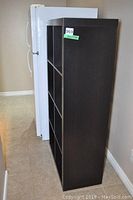 Side view of the dark wood cubed bookshelf next to a white refrigerator.