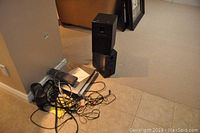 Sony home theatre system parts including speakers and cables on floor near wall and carpet.