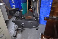 Side view of the black Vision Fitness stationary bike showing the seat, pedals, and part of the console in a storage room.