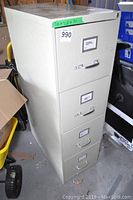 Side view of beige metal 4-drawer filing cabinet showing the cabinet height, handle design, and wear marks.