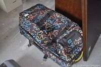 Overall view of Burton snowboarding bag showing colorful squiggly line print, adjustable straps, and handles.