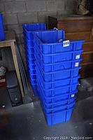 Stacked blue plastic recycling bins, about 20 in total, showing the height and shape of the bins.