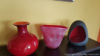 Set of 3 red decor items including glossy vase, frosted vase and black/red sculptural piece
