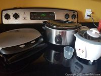 All three appliances together on stove: rice cooker, slow cooker, and electric grill