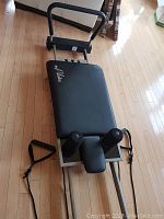 Full view of reformer frame, sliding carriage with footbar and spring tension adjusters