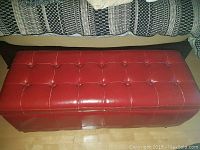 Red faux leather storage chest with tufted design closed, showing size and condition.