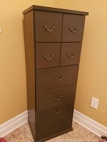 Front view of dark brown storage cabinet with 7 drawers, showing all handles and general shape.