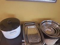 Shows the white enamel pot with lid, three rectangular metal casserole dishes, five nested metal mixing bowls.