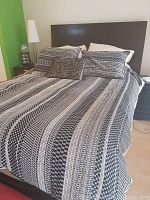 Full view of queen-size bed made with Glucksteinhome black and brown patterned duvet cover and two matching pillowcases, small Calvin Klein decorative pillow visible on bed