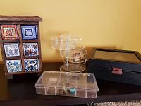 Photo showing wooden jewelry box with colorful drawer tiles, clear acrylic round and rectangular organizers, and dark brown watch case with transparent lid.