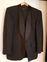 Black tuxedo jacket with satin lapels hanging on wooden hanger
