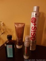 Schwarzkopf OSiS+ hairspray, OSiS serum, Moroccan Oil Treatment, and Brazilian Blowout masque on table under yellow light.