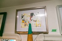 Framed abstract painting with predominantly white, yellow, and orange tones, framed in a silver frame.