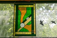 Full view of the stained glass panel hung on a window showing the colors and design