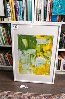 Original abstract art painting in white frame leaning against bookshelf with books behind it.