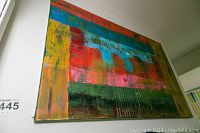 Front angle photo showing the full abstract oil painting with colorful horizontal and vertical elements in red, blue, green, and yellow tones.