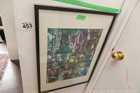 Framed abstract art resting against a white door and wall, showing the overall piece and frame.