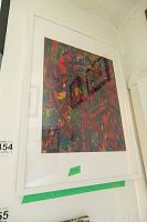 Framed abstract colorful artwork by Alex Hare hung on a wall, shown angled with reflections on glass.