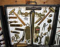 Pegboard case showing full array of brass tools and fittings including mallets, scale, bells, ruler and door hardware