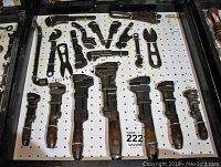 Full view of pegboard panel with six wooden-handled adjustable wrenches at bottom and assorted small wrenches at top