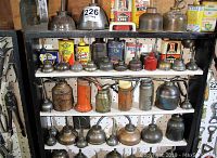 Overall view of three-tier shelf filled with various metal oil cans and tins