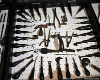 Full view of black wooden pegboard case showing mounted tools including bevelers, awls, irons, pliers and other hand tools.