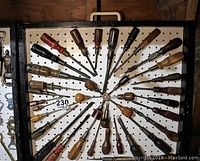 Image showing about 40 vintage screwdrivers organized in a radial pattern on a white pegboard, mounted in a black frame with a handle.