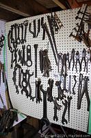 Pegboard with a large assortment of vintage hand tools including wrenches, pliers, and other gripping tools hanging organized by type and size.