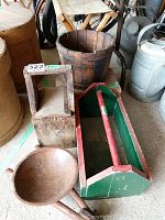 Photo showing wooden tool box, wooden bucket, wooden wheelbarrow bowl with wheel, and foot stool arranged on floor.