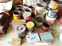 Wide view of approximately 25 vintage tobacco and cigarette collectible tins showing various brands and sizes arranged on a wooden table.