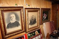 Three framed pieces mounted on plywood wall: two portraits and one floral still life