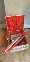 Photo of open wicker sewing basket with sewing supplies inside showing red satin lining and sewing needles