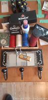Full view photo of the poker chips, bottle openers, spray bottles, sunglasses pouch, and wooden rack with hooks on a wooden surface.