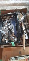 Basket with mixed silverware and cooking utensils including whisks, ladle, peelers, and spoons