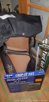 Golf bag with strap in black and brown colors beside boxed Top-Flite Chip-It Net and a Yard Golf practice tool box, showing logos and condition of the items.