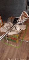 Two lacrosse sticks, ball, and protective gear including gloves, arm pads, and shoulder pads appear in a box.