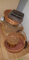 Multiple wicker and woven baskets stacked and arranged showing different sizes and shapes, some with handles and one with compartments.