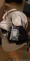 Top view of multiple items including white woven sun hats, various purses and bags, and a wallet with maxsold lot tag included.