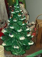 Vintage green ceramic Christmas tree missing star and some lights, showing bulb holders and partial colored bulbs