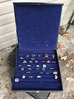 Blue velvet hinged box open showing full set of rings on seven horizontal rolls