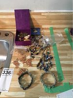 Image showing purple jewelry box with assorted bracelets and earrings laid out on a wooden surface.