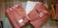Three wool blankets; two rust-colored with satin edges and one plain white wool blanket.